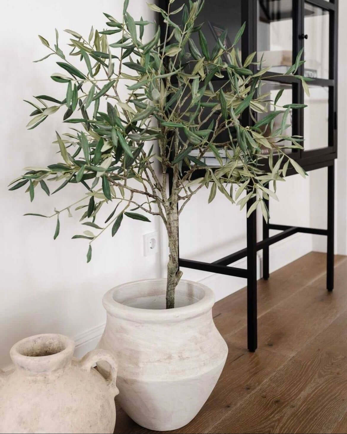 Artificial olive tree in a white pot, adding elegant Mediterranean decor to indoor space without maintenance.