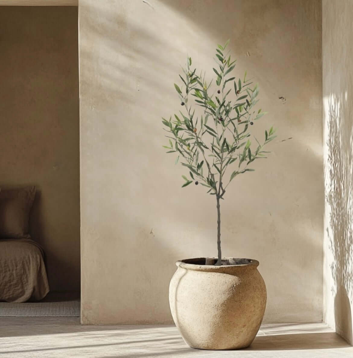 Artificial olive tree in a rustic pot in a sunlit room, bringing natural elegance without maintenance.