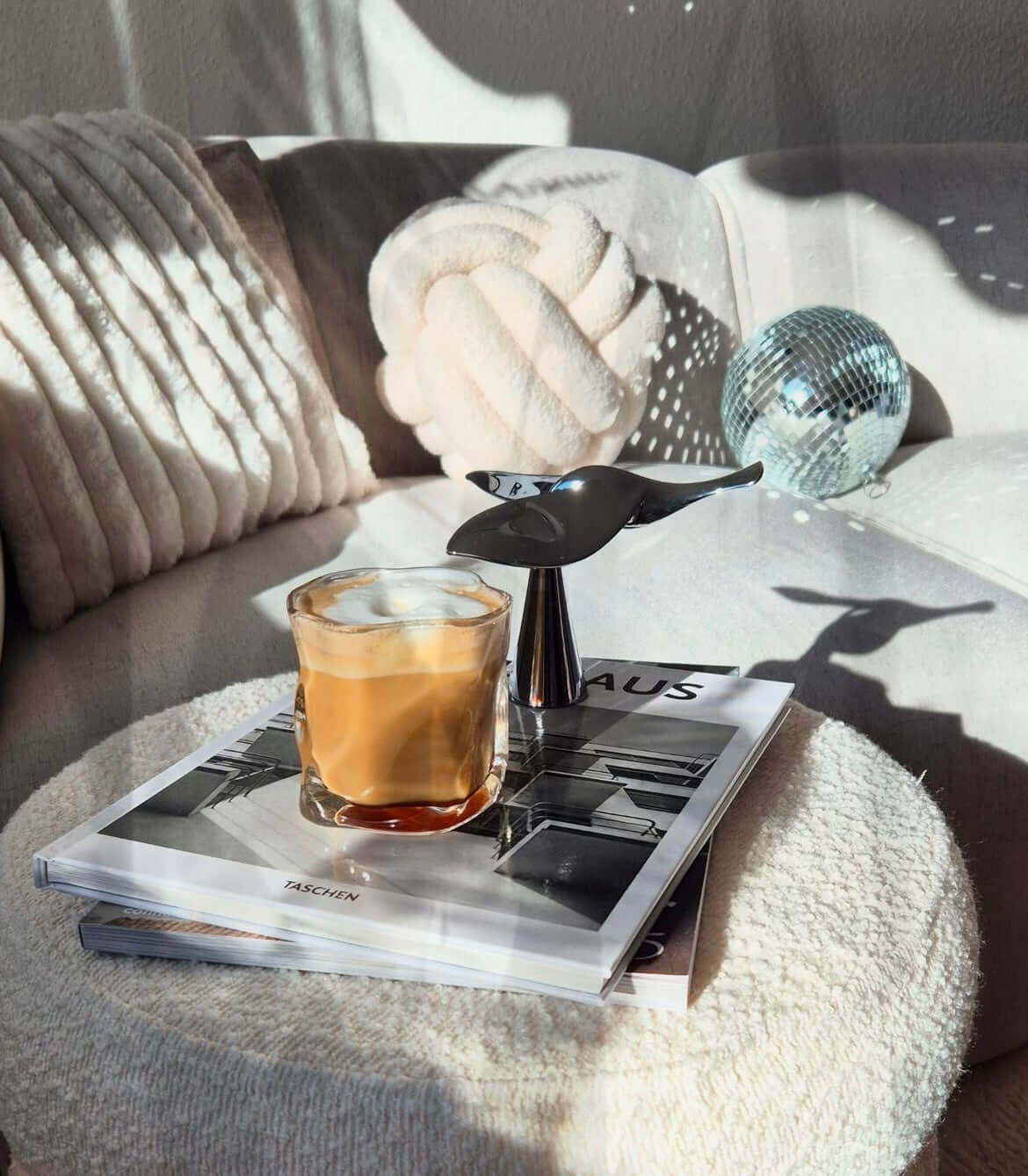 Fliegender Vogel-Flaschenöffner auf Tisch mit Kaffee und Büchern, modernes Design, Balance-Effekt Deko in sonnigem Wohnzimmer.