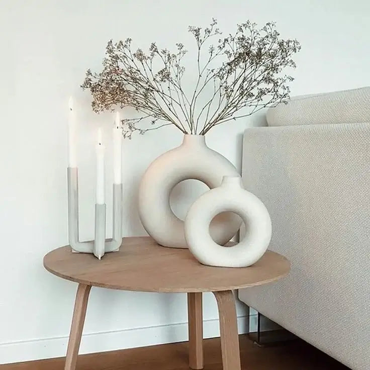 Set of two Nordic vases on a wooden table, featuring minimalist design and dried branches, next to a candle holder.