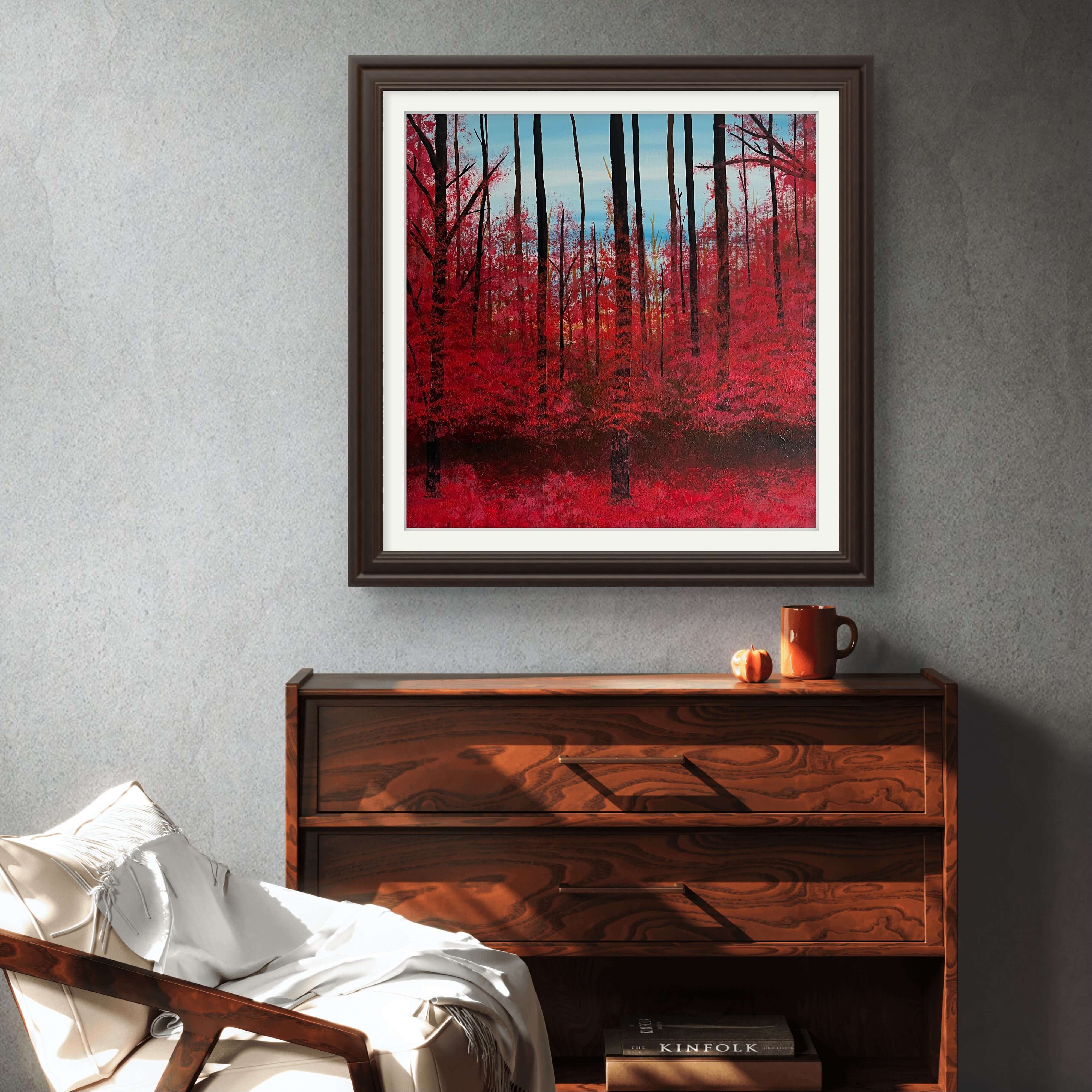 Hand-painted acrylic artwork 'Roter Wald' depicting a blazing autumn forest in red with a serene blue sky, framed on a grey wall.