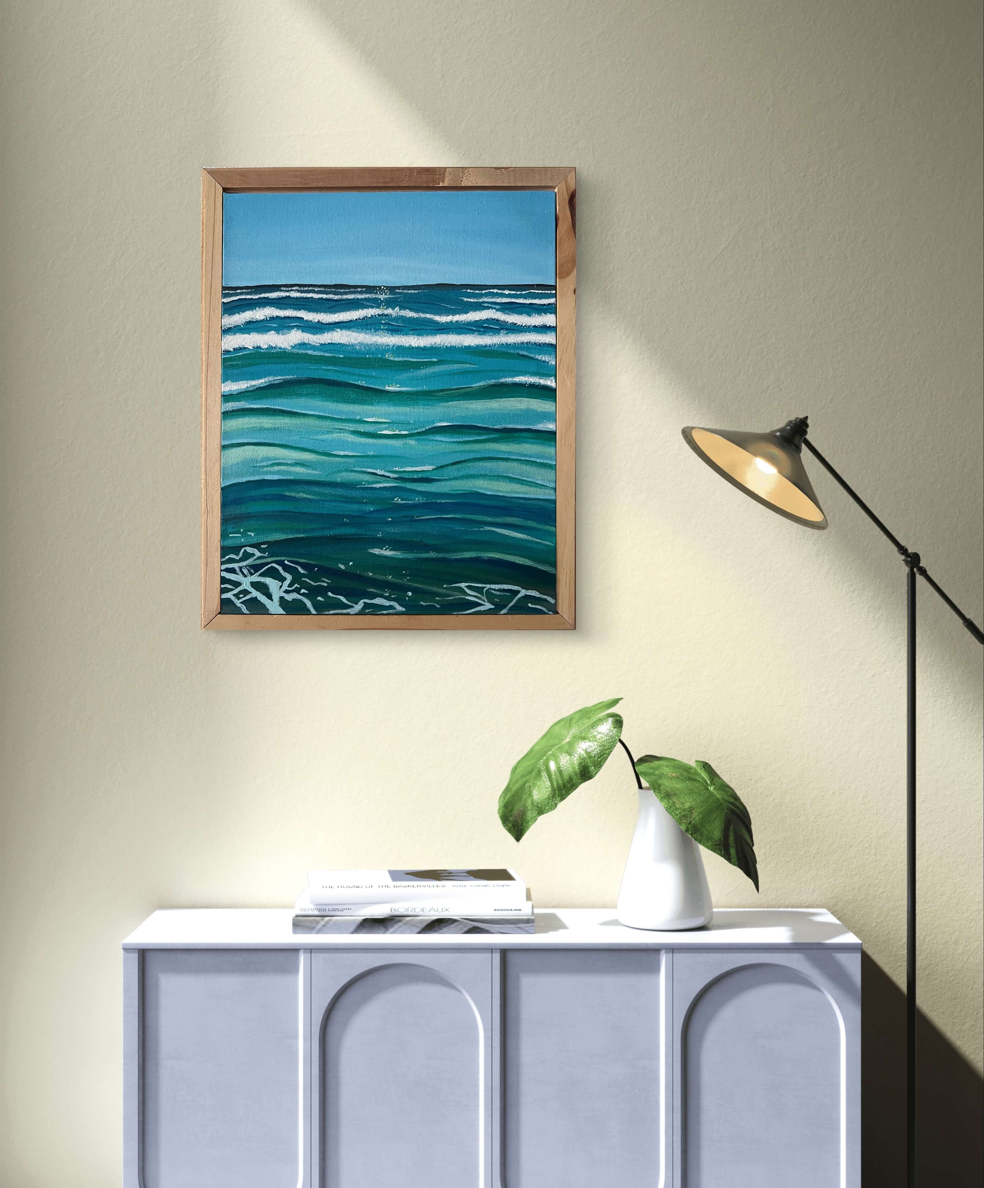 Hand-painted acrylic ocean art "Meeresharmonie" in blue and green tones hung above a cabinet with plant decor.