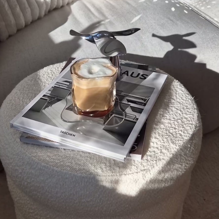 Fliegender Vogel-Flaschenöffner balanciert knackig über einem Kaffee auf einem Tisch, stilvolle Balance mit einzigartigem Design.