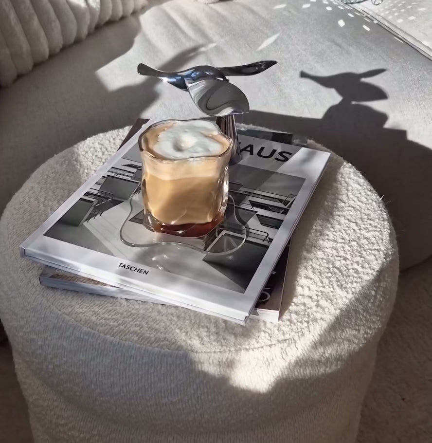 Fliegender Vogel-Flaschenöffner balanciert knackig über einem Kaffee auf einem Tisch, stilvolle Balance mit einzigartigem Design.