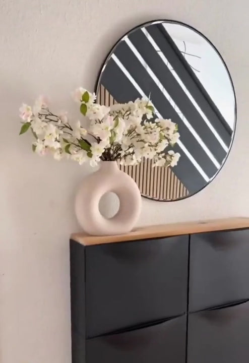 Modern interior with Nordic vase on cabinet, featuring minimalist flowers and round mirror, showcasing Scandinavian elegance.