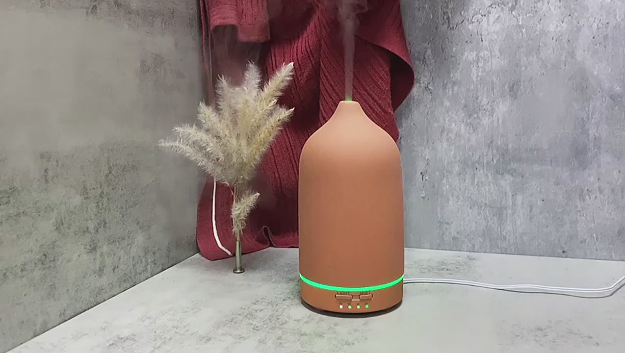 Ultraschall-Aromatherapie-Diffusor in modernem Design auf einem Tisch, umgeben von dekorativen Elementen im Wohnzimmer.